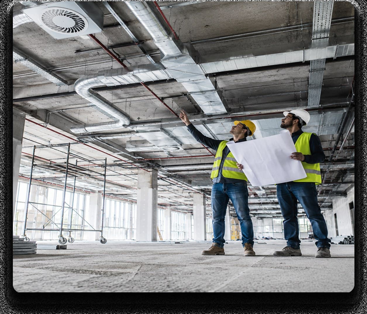 Doi ingineri examinând planul de instalații pe șantierul unei clădiri în construcție